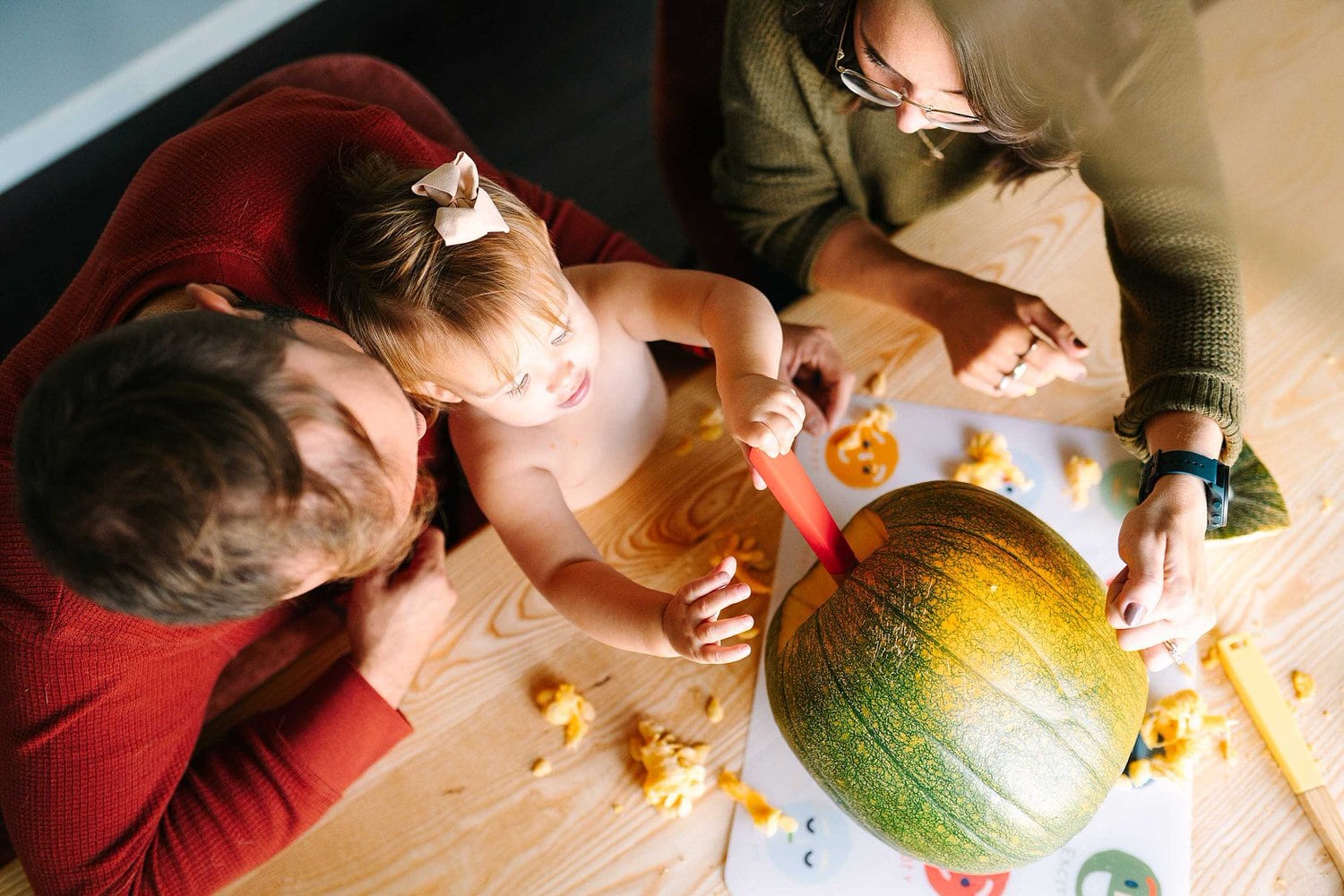 A little girl scoops seeds out of a pumpkin