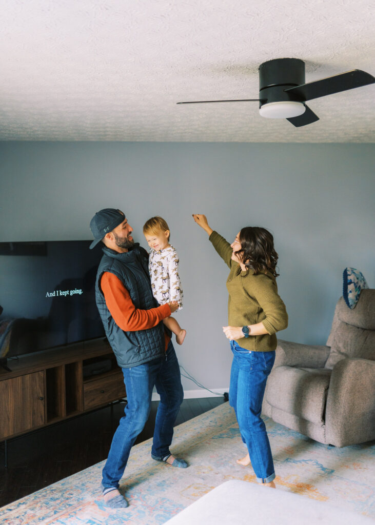 A family dances in the living room in front of the TV. There is text on the TV screen that says "we kept going"