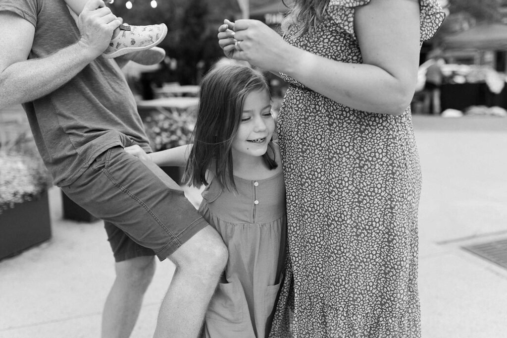 A little girl squeezes in between her mom and dad smiling
