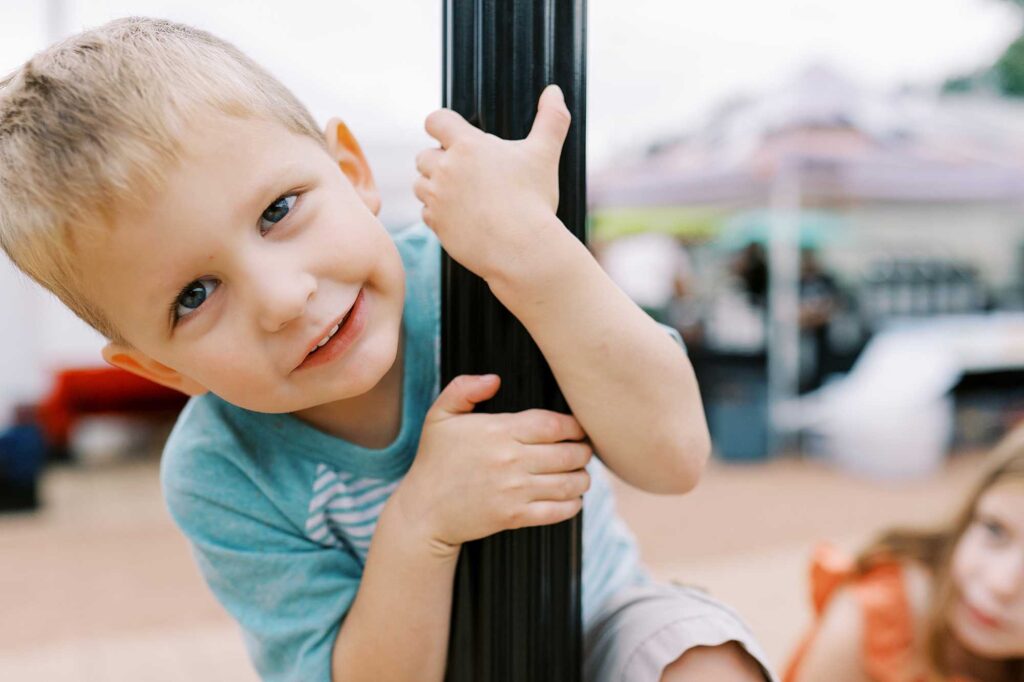 A little boy hanging onto a lamp post and peeking around it