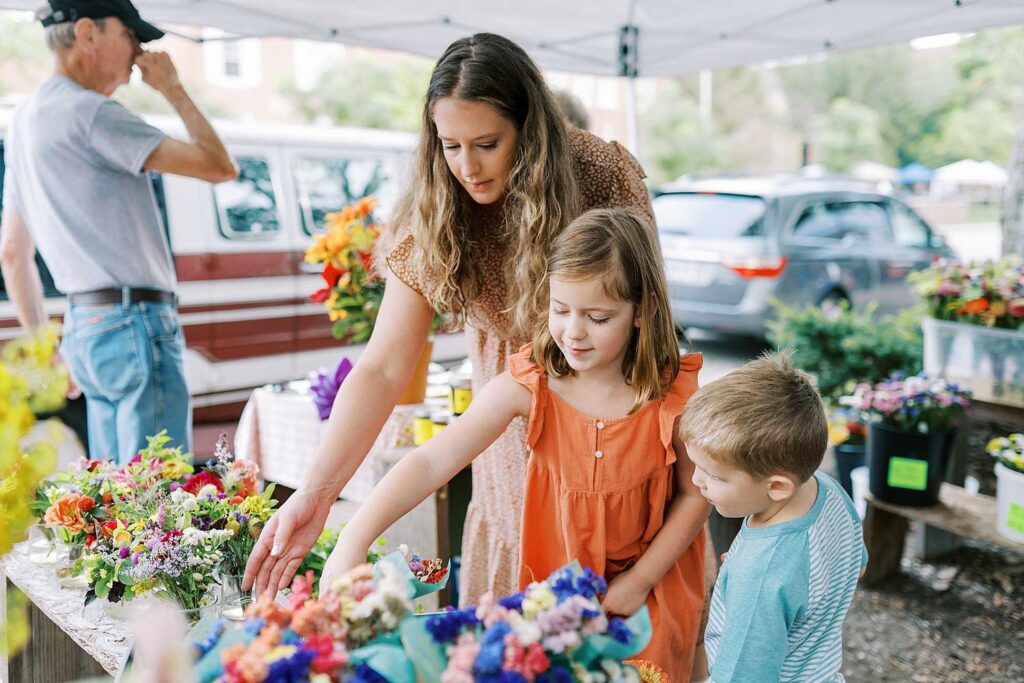 A mom and her two kids pick flower arrangements at the worthington ohio farmers market