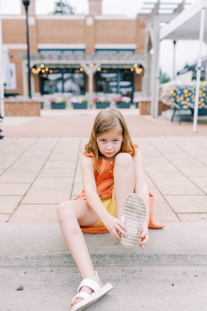 A little girl puts on her sandal