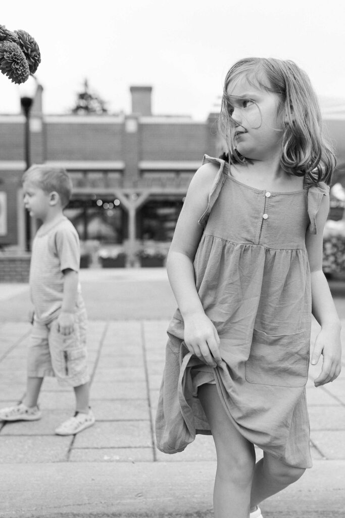 A little girl walking away from her brother