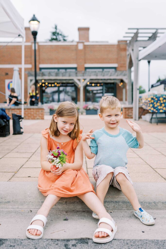 A brother and sister sitting on the curb at the worthington ohio farmers market