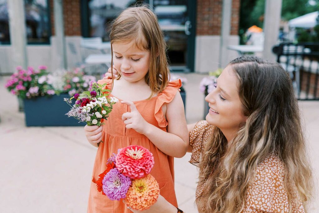 A little girl and her mom both holding wildflower bouquets 