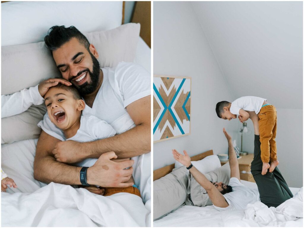 A dad playfully wrestles with his young son in their bed