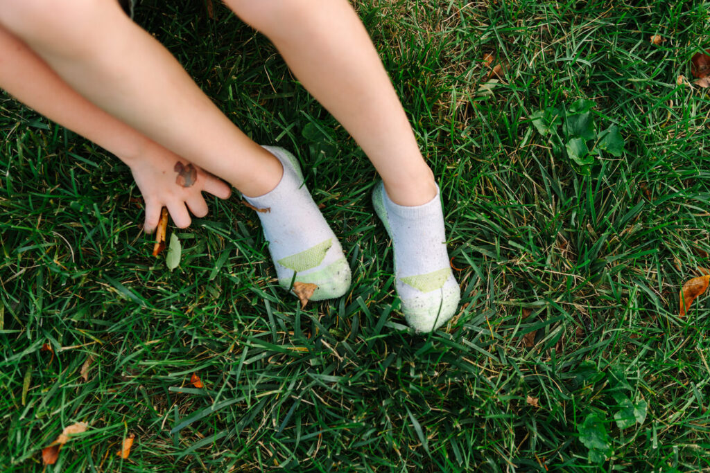 A child's feet wearing socks in a patch of green summer grass