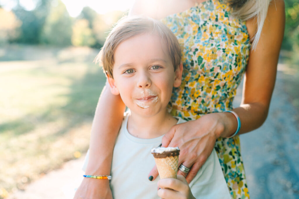 A young boy smiling with melting ice cream on his face during sunset in Columbus Ohio, captured by lifestyle photographer Daisy Zimmer