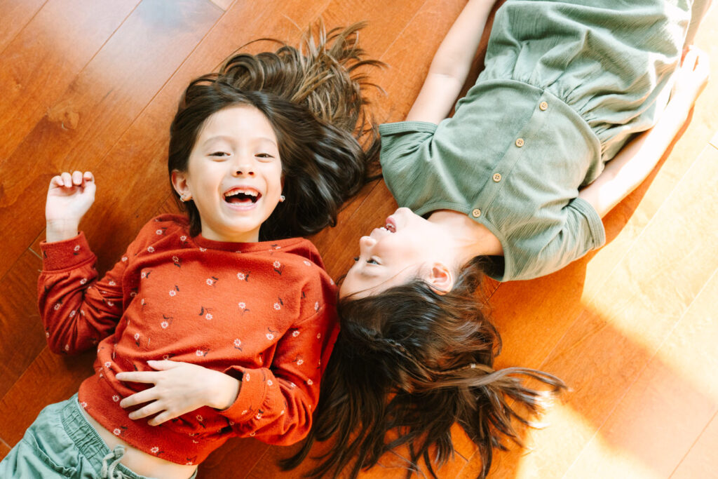 Two sisters laughing on the floor at their house in Columbus Ohio