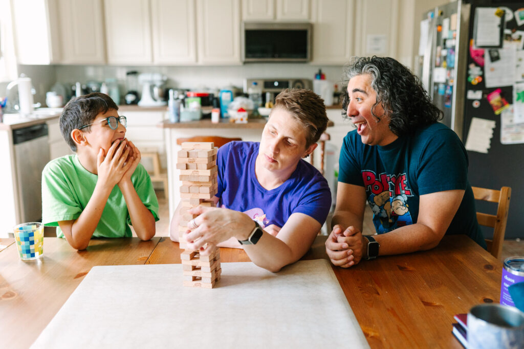Rachael pulls out a Jenga piece hesitantly while her son and husband giggle behind her back, a moment captured by lifestyle photographer Daisy Zimmer