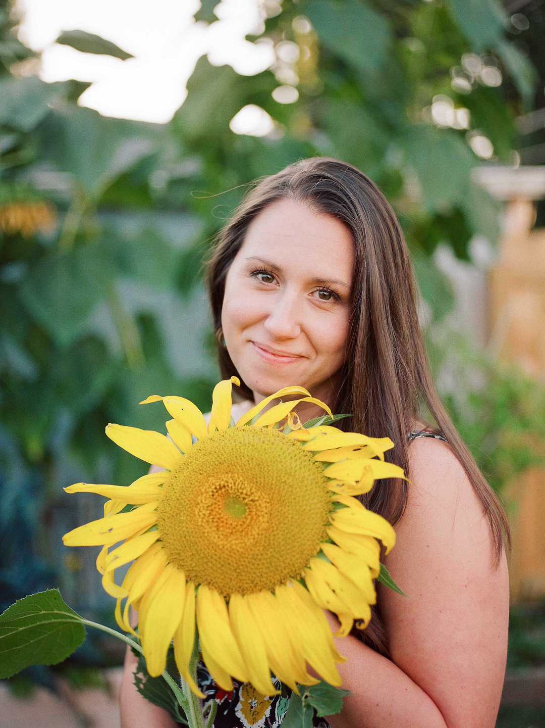 a lady holding a giant sunflower and smiling