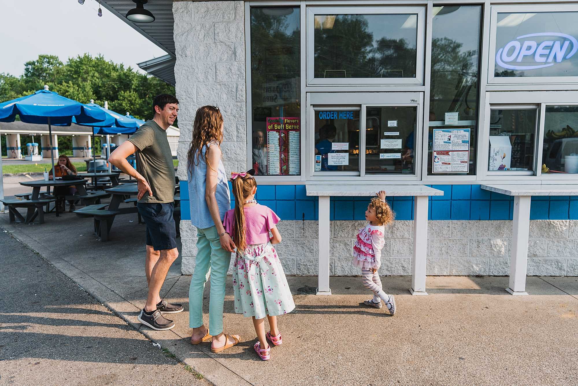 A family standing at the pick-up window of an ice cream shop