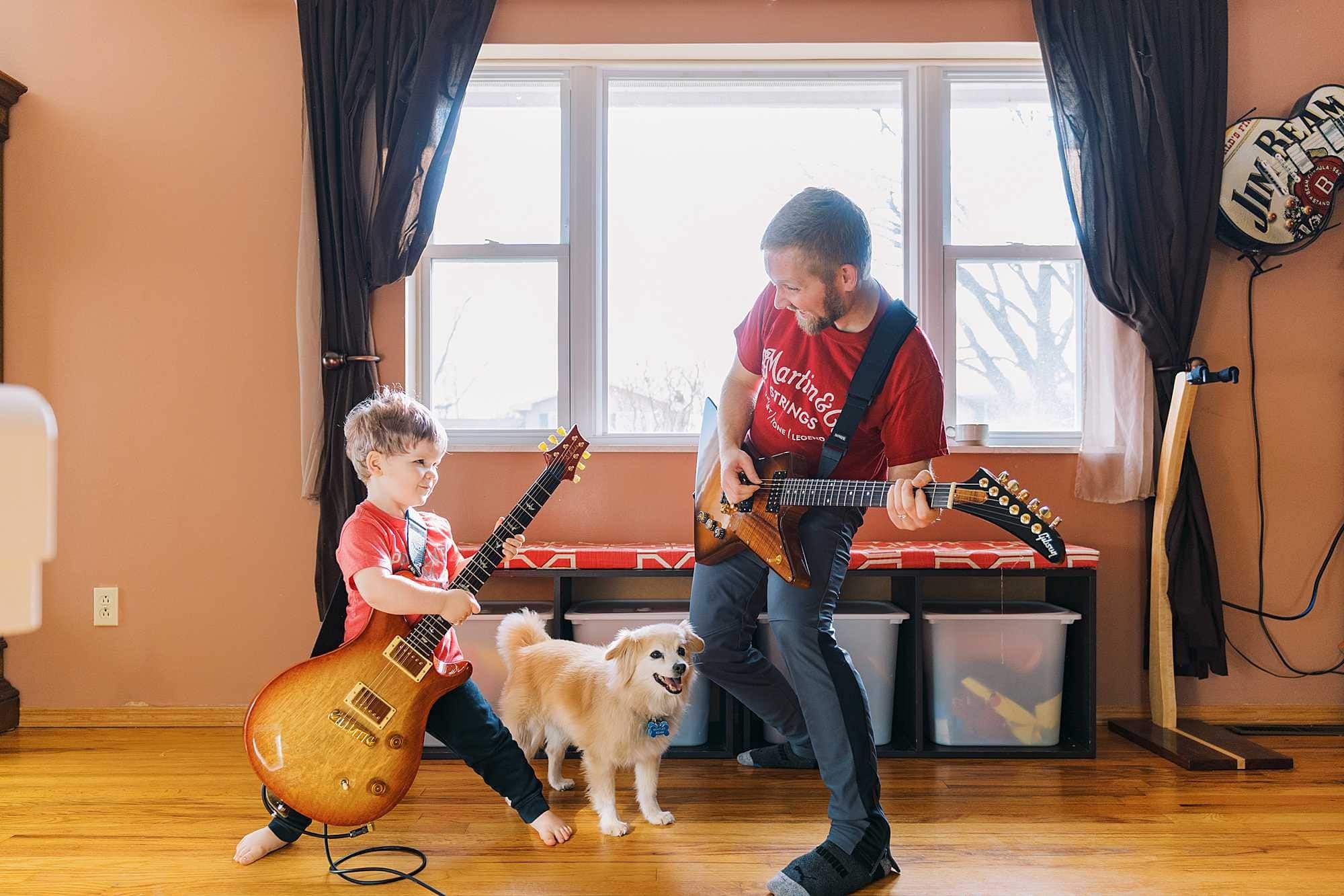 Coledyn plays electric guitar with his dad in front of a big living room window in their home in Columbus Ohio