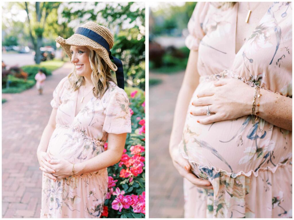 A pregnant lady wearing a straw hat standing in front of a pink rosebush