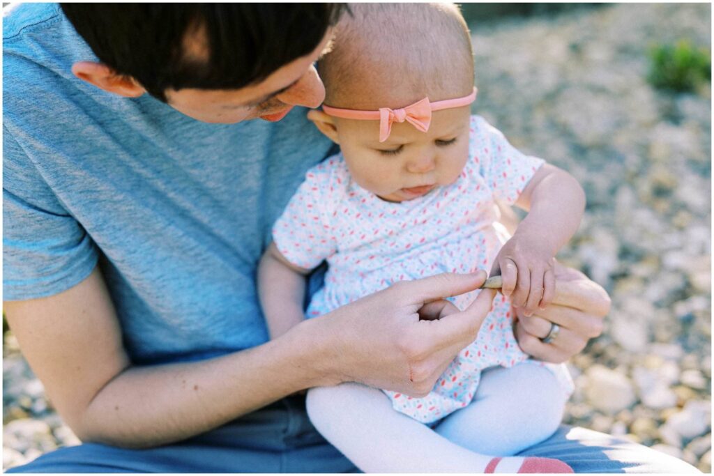 A dad handing his baby a tiny seashell at Scioto Grove Metropark in Ohio