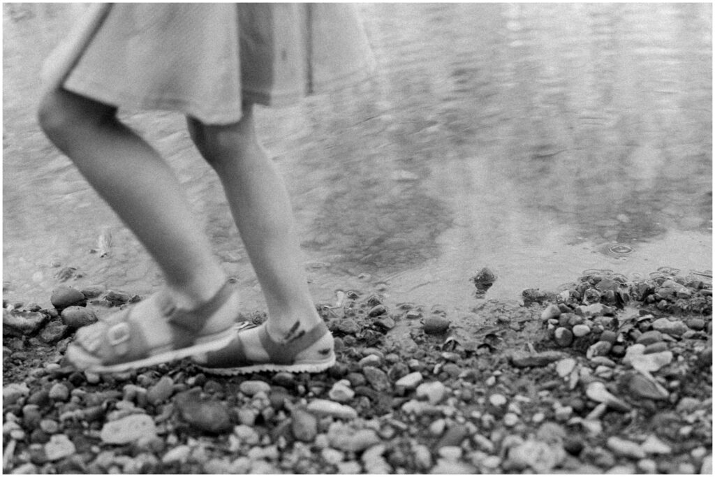 A little girl's blurry feet running through pebbles at the side of a stream in Columbus Ohio