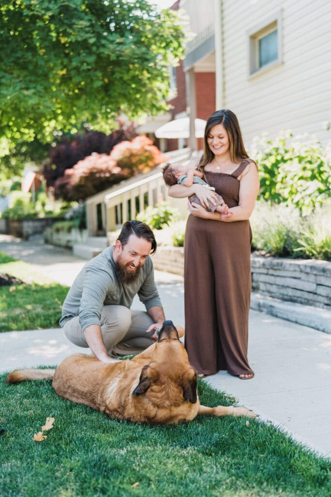 Adam and Megan stand outside their home in Columbus Ohio with their newborn baby and large dog