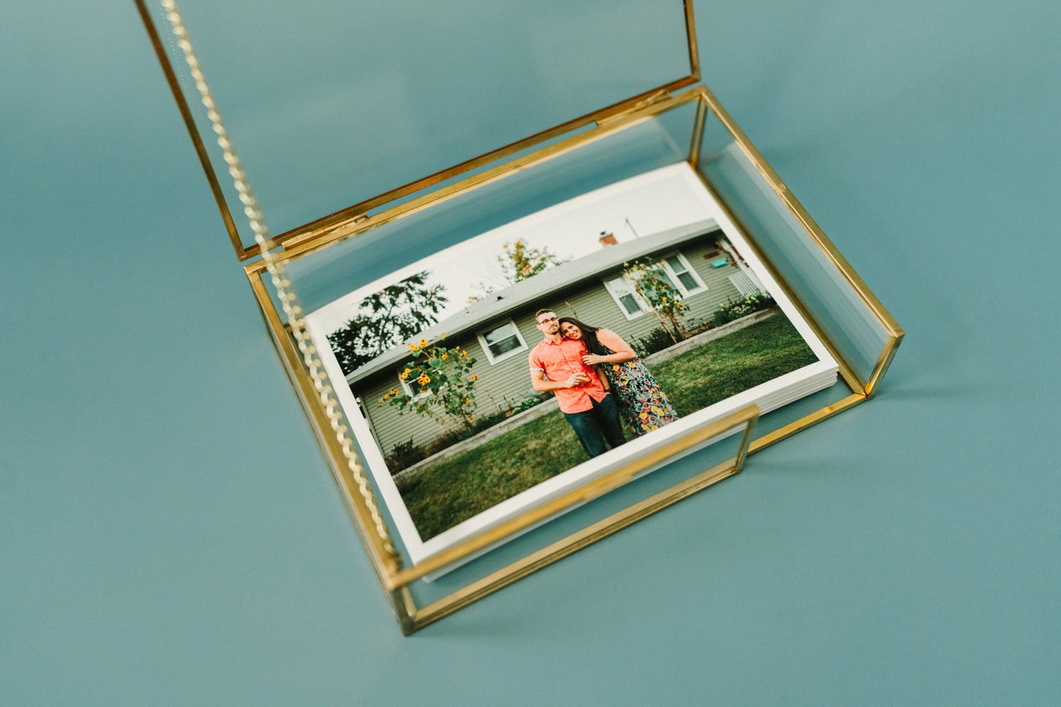 A stack of photo prints inside of a glass box with gold trim