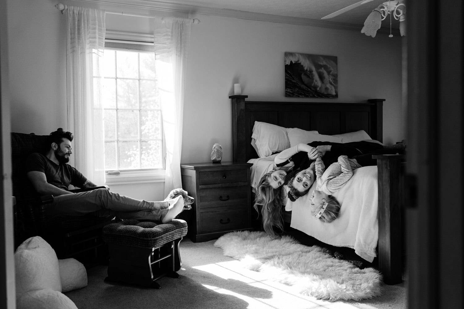 a mom and her two daughters on a bed laughing in a candid moment captured by lifestyle photographer Daisy Zimmer