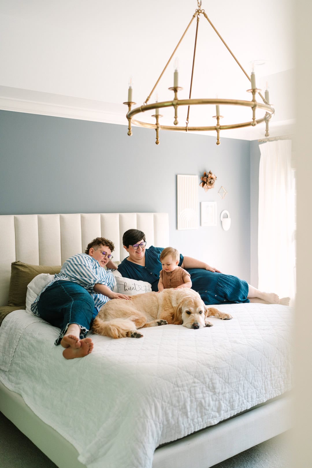family cuddling on the bed with their goldendoodle dog