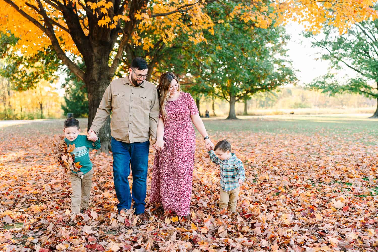 A family with two young boys walks under a tree during a fall mini session in Columbus Ohio