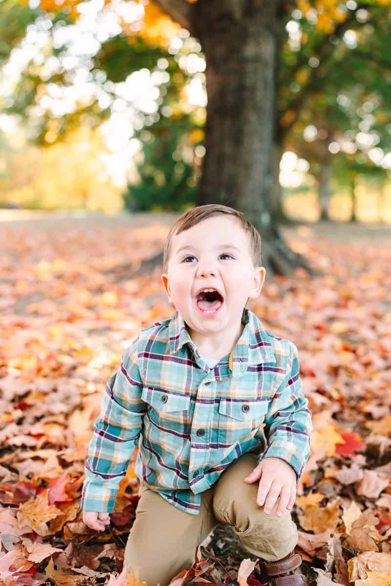A young boy opening his mouth wide and smiling, captured during a fall mini session by Daisy Zimmer Photography